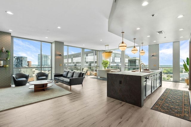 900 20th Ave S Unit 1601, Nashville, TN 37212 - kitchen featuring a wall of windows, a view of city, light wood finished floors, decorative light fixtures, and a kitchen island with sink
