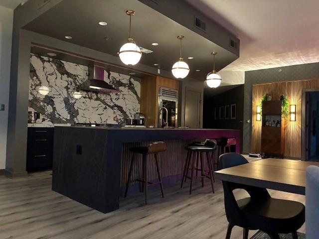 900 20th Ave S Unit 1601, Nashville, TN 37212 - community bar area with wall chimney exhaust hood, light wood-style flooring, hanging light fixtures, fridge, and recessed lighting