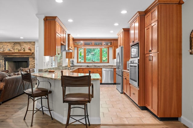 204 Chapman Ct, La Fayette, GA 30728 - kitchen featuring appliances with stainless steel finishes, a peninsula, a sink, light stone countertops, and a kitchen bar