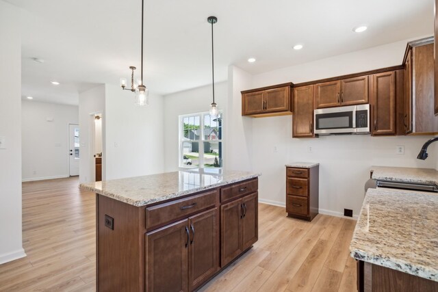 1441 Isaiah Dr, Clarksville, TN 37042 - kitchen with stainless steel microwave, light wood-style floors, a sink, pendant lighting, and light stone countertops