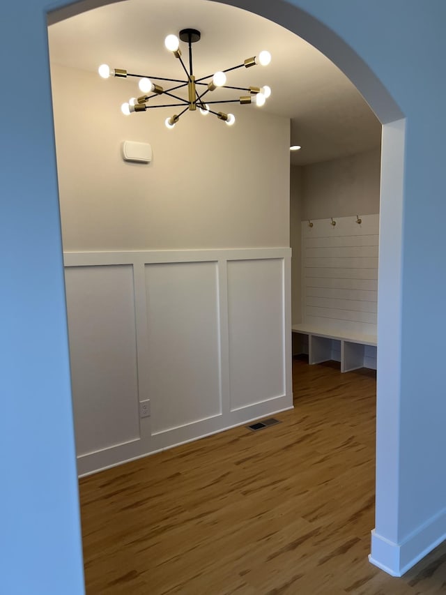 281 Bluebell Dr, Clarksville, TN 37043 - empty room with arched walkways, a chandelier, wood finished floors, a decorative wall, and wainscoting