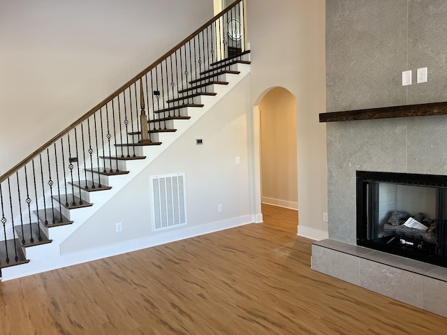 281 Bluebell Dr, Clarksville, TN 37043 - unfurnished living room featuring baseboards, wood finished floors, arched walkways, stairs, and a fireplace