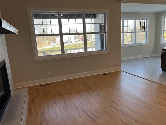 281 Bluebell Dr, Clarksville, TN 37043 - unfurnished living room with a fireplace with flush hearth, baseboards, wood finished floors, and a chandelier