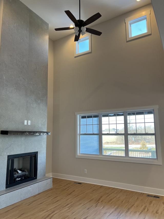 281 Bluebell Dr, Clarksville, TN 37043 - unfurnished living room with wood finished floors, a fireplace, ceiling fan, a high ceiling, and baseboards