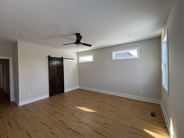 281 Bluebell Dr, Clarksville, TN 37043 - unfurnished bedroom with a barn door, wood finished floors, baseboards, a ceiling fan, and recessed lighting