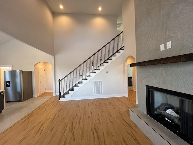 281 Bluebell Dr, Clarksville, TN 37043 - unfurnished living room featuring arched walkways, a towering ceiling, baseboards, stairs, and light wood-type flooring