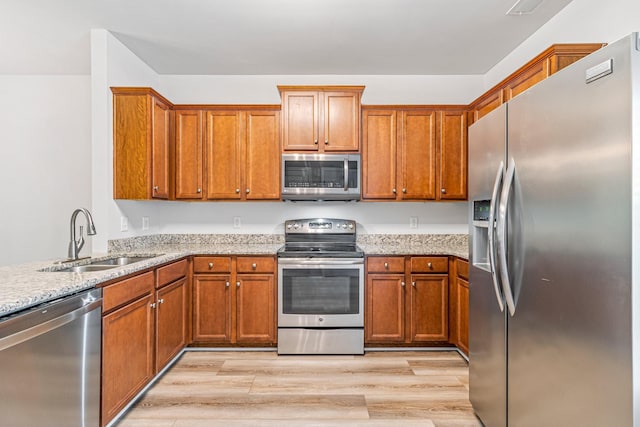 913 Battleview Pl, Murfreesboro, TN 37128 - kitchen featuring stainless steel appliances, a sink, brown cabinets, light wood-style floors, and light stone counters