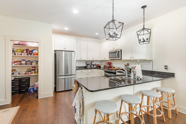 201 Hart Ln, Lebanon, TN 37087 - kitchen with appliances with stainless steel finishes, a peninsula, dark wood-style flooring, white cabinetry, and tasteful backsplash