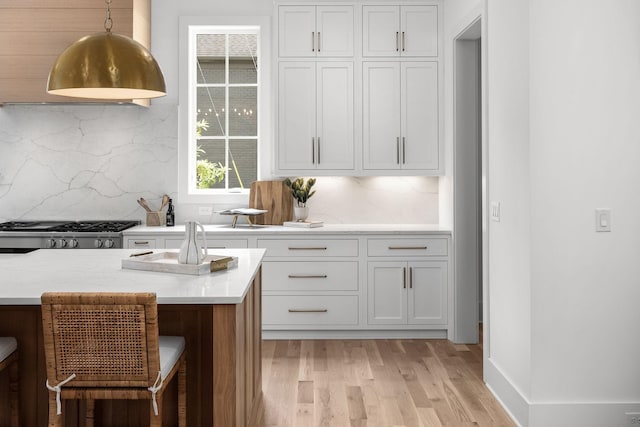 609 Bowling Ave, Nashville, TN 37215 - kitchen with light wood finished floors, decorative backsplash, pendant lighting, a kitchen bar, and white cabinetry