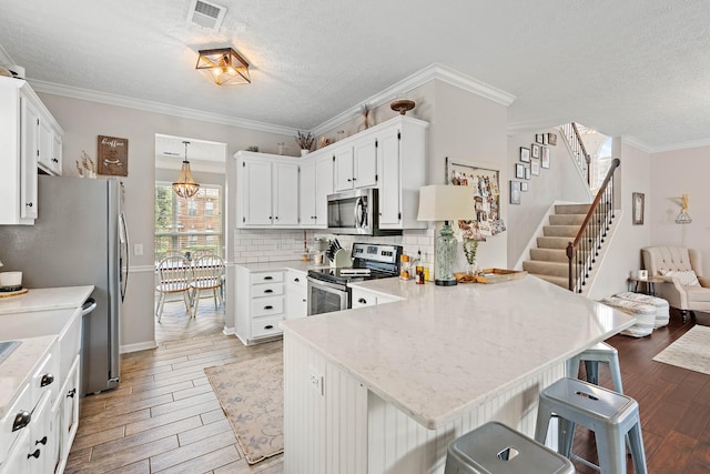 503 Hollyhock Way, Franklin, TN 37064 - kitchen with appliances with stainless steel finishes, a peninsula, light wood-style floors, a textured ceiling, and decorative backsplash