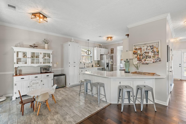 503 Hollyhock Way, Franklin, TN 37064 - kitchen featuring stainless steel fridge, a peninsula, a kitchen breakfast bar, a textured ceiling, and wood finished floors