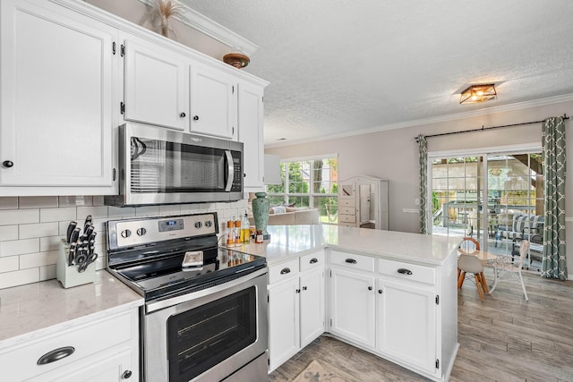 503 Hollyhock Way, Franklin, TN 37064 - kitchen featuring appliances with stainless steel finishes, a textured ceiling, a peninsula, crown molding, and white cabinets