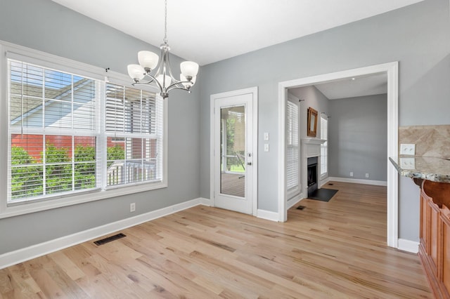 193 Red Jacket Trce, Murfreesboro, TN 37127 - unfurnished dining area featuring light wood-style floors, a chandelier, baseboards, and a fireplace with flush hearth