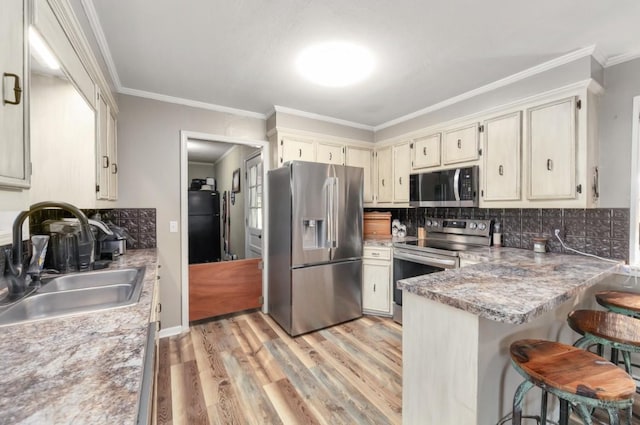 235 Pinecrest Dr, Henderson, TN 38340 - kitchen featuring stainless steel appliances, a sink, light wood-style floors, decorative backsplash, and crown molding