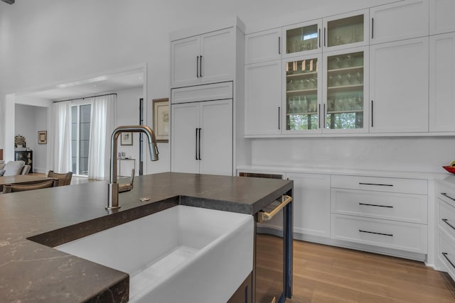 7313 Harlow Dr, College Grove, TN 37046 - kitchen with a sink, white cabinetry, paneled built in fridge, light wood-style floors, and glass insert cabinets