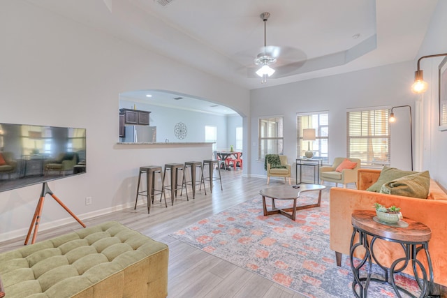 5115 Heroes Ln, Murfreesboro, TN 37129 - living room featuring arched walkways, plenty of natural light, a tray ceiling, and light wood-style floors