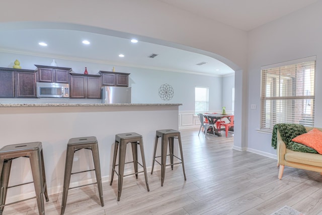 5115 Heroes Ln, Murfreesboro, TN 37129 - kitchen featuring stainless steel appliances, arched walkways, a kitchen breakfast bar, dark brown cabinetry, and crown molding