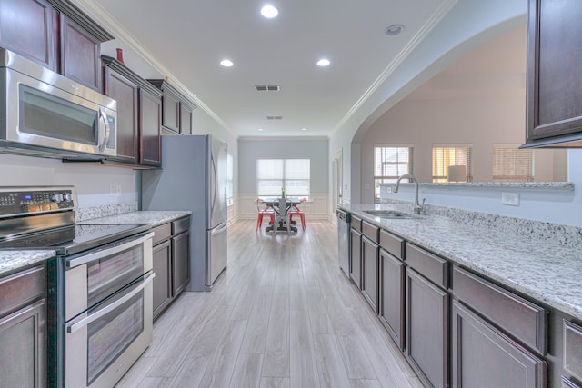 5115 Heroes Ln, Murfreesboro, TN 37129 - kitchen with stainless steel appliances, arched walkways, a sink, crown molding, and light stone countertops