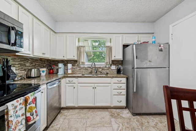 4904 Rainier Dr, Old Hickory, TN 37138 - kitchen with appliances with stainless steel finishes, a sink, decorative backsplash, white cabinets, and a textured ceiling