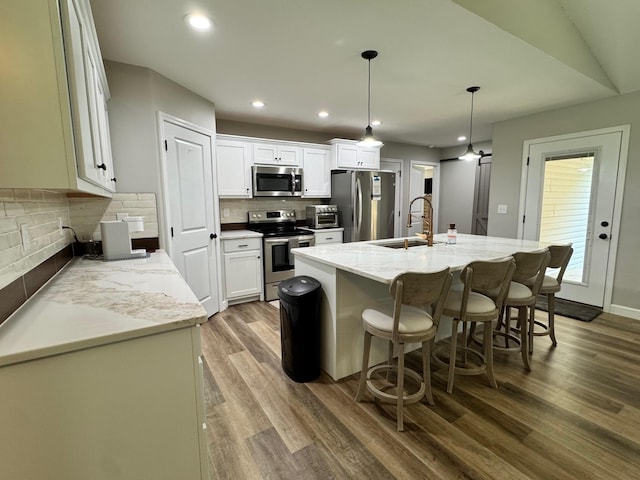 111 Stellar Ct, Clarkrange, TN 38553 - kitchen with appliances with stainless steel finishes, a sink, wood finished floors, backsplash, and an island with sink