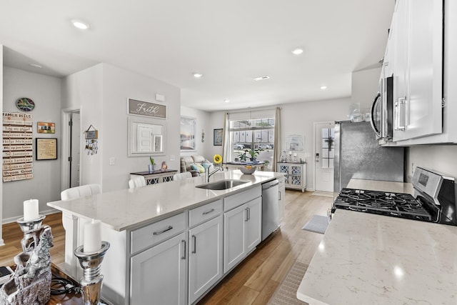2563 Drumwright Way, Columbia, TN 38401 - kitchen featuring stainless steel appliances, light wood-type flooring, a kitchen island with sink, a sink, and white cabinetry