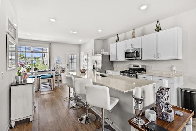 2563 Drumwright Way, Columbia, TN 38401 - kitchen featuring stainless steel appliances, a breakfast bar area, white cabinetry, an island with sink, and wood finished floors