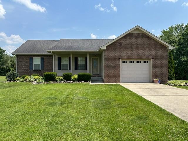 1056 Orion Jones Rd, Chapmansboro, TN 37035 - single story home with brick siding, driveway, an attached garage, and a front lawn