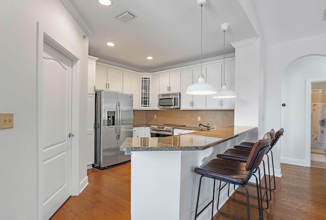 309 Seven Springs Way Unit 404, Brentwood, TN 37027 - kitchen featuring stainless steel appliances, arched walkways, glass insert cabinets, a peninsula, and white cabinets