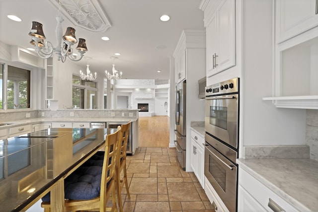 1853 Lafever Ridge Rd, Silver Point, TN 38582 - kitchen featuring appliances with stainless steel finishes, stone tile flooring, a chandelier, open floor plan, and white cabinetry