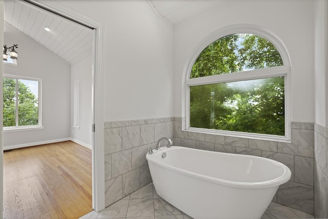 1853 Lafever Ridge Rd, Silver Point, TN 38582 - bathroom featuring tile walls, a soaking tub, vaulted ceiling, wainscoting, and wood finished floors