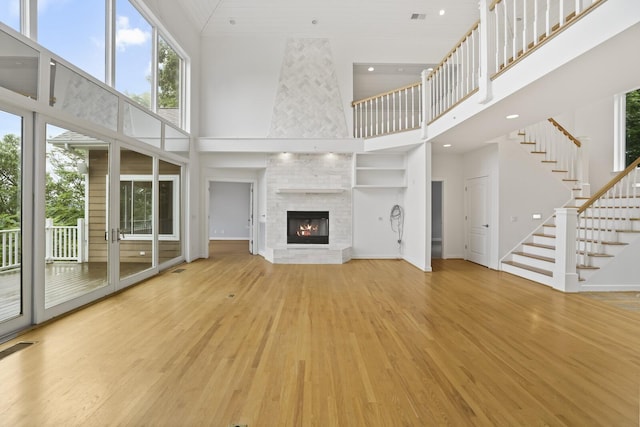 1853 Lafever Ridge Rd, Silver Point, TN 38582 - unfurnished living room featuring a towering ceiling, wood finished floors, a fireplace, stairway, and recessed lighting