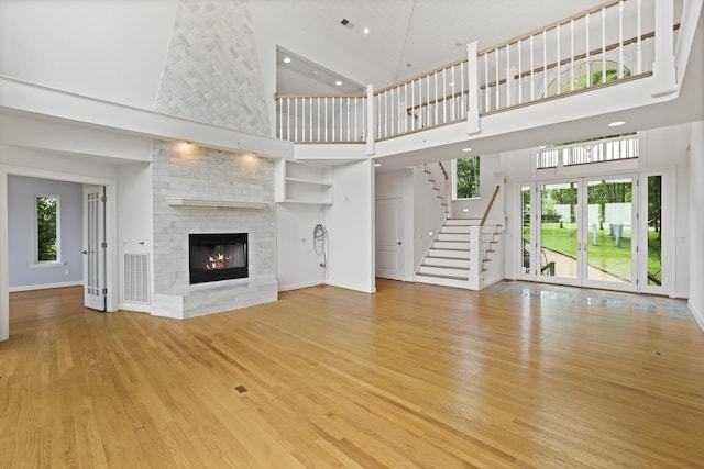 1853 Lafever Ridge Rd, Silver Point, TN 38582 - unfurnished living room with a towering ceiling, light wood-style flooring, a large fireplace, stairway, and recessed lighting