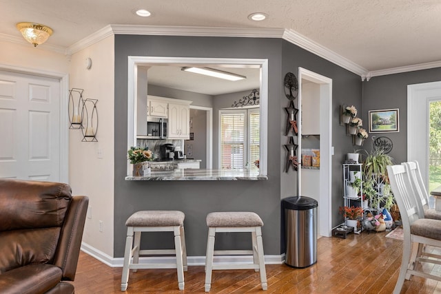 154 Jasons Way, Leoma, TN 38468 - kitchen featuring stainless steel microwave, wood finished floors, a breakfast bar, white cabinetry, and baseboards