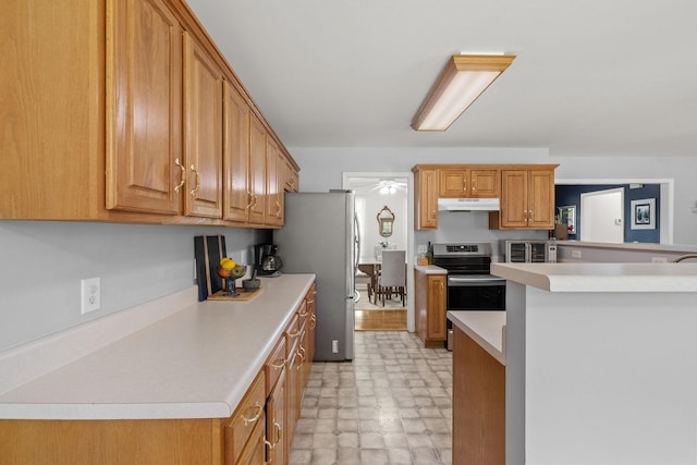 4291 Skelley Rd, Santa Fe, TN 38482 - kitchen with under cabinet range hood, stainless steel appliances, light countertops, ceiling fan, and brown cabinetry