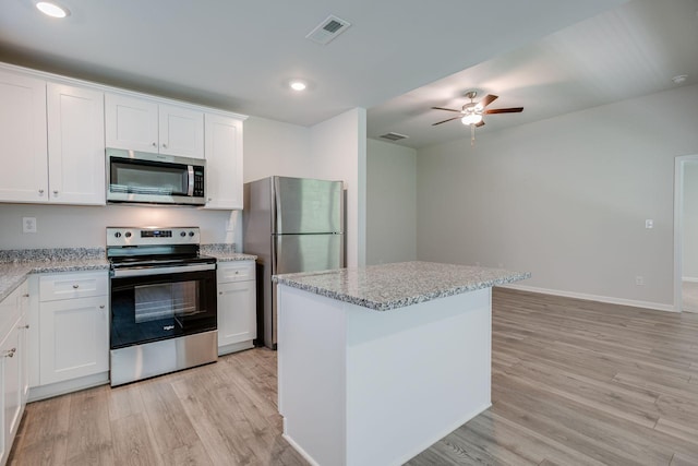 1003 Autumnwood Dr, Dickson, TN 37055 - kitchen featuring appliances with stainless steel finishes, light wood-style flooring, ceiling fan, white cabinetry, and light stone counters