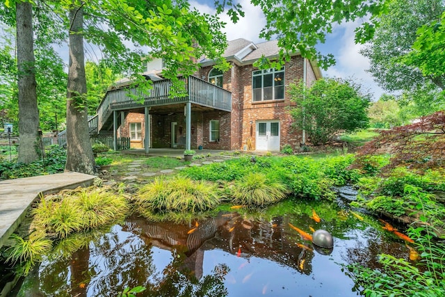 4090 Ironwood Dr, Greenbrier, TN 37073 - back of property with brick siding, a wooden deck, a small pond, stairway, and french doors