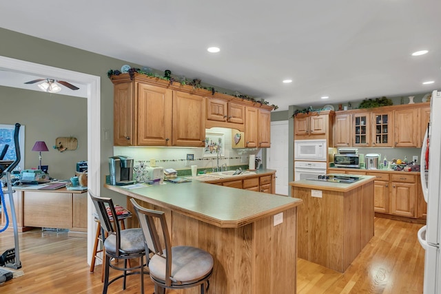 4090 Ironwood Dr, Greenbrier, TN 37073 - kitchen featuring white appliances, a sink, a center island, light countertops, and light wood finished floors