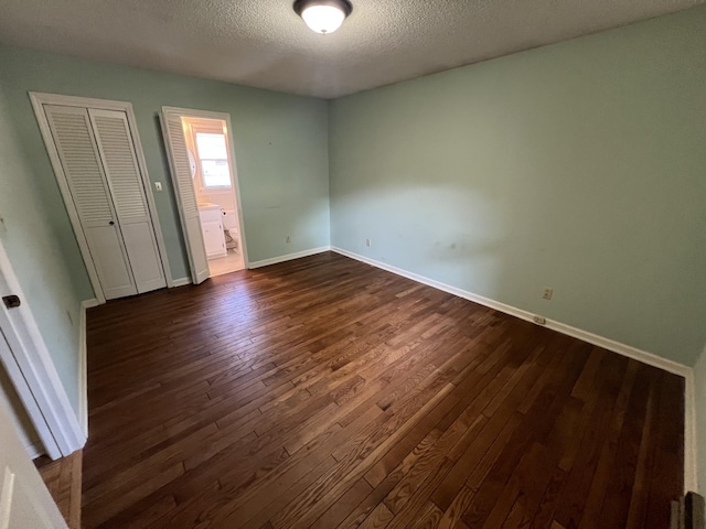 212 N 3rd St, Pulaski, TN 38478 - unfurnished bedroom with dark wood-type flooring, a textured ceiling, baseboards, connected bathroom, and a closet