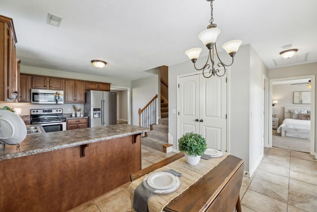 4219 Zephyr Ct, Murfreesboro, TN 37128 - kitchen with stainless steel appliances, light tile patterned floors, a peninsula, brown cabinetry, and a kitchen breakfast bar