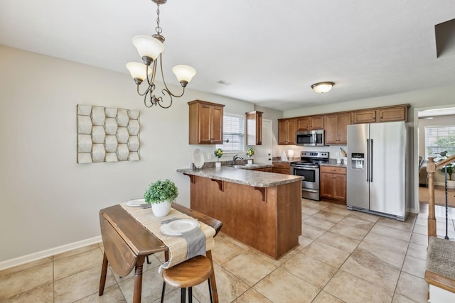 4219 Zephyr Ct, Murfreesboro, TN 37128 - kitchen featuring stainless steel appliances, a peninsula, a sink, brown cabinets, and a kitchen breakfast bar