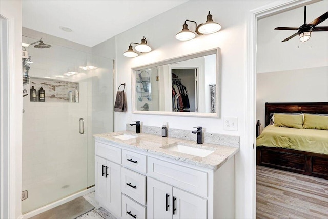 3128 Crow Rd NE, Dalton, GA 30721 - full bathroom featuring a stall shower, ceiling fan, double vanity, a spacious closet, and wood finished floors
