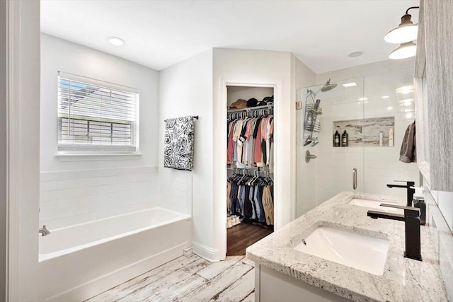 3128 Crow Rd NE, Dalton, GA 30721 - bathroom featuring a garden tub, a spacious closet, a stall shower, wood finished floors, and double vanity