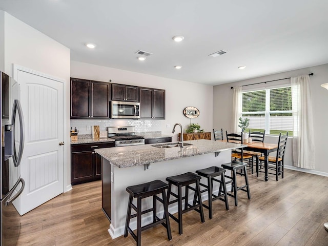 7231 Carrie Ct, Antioch, TN 37013 - kitchen with appliances with stainless steel finishes, a sink, a kitchen breakfast bar, light wood finished floors, and recessed lighting