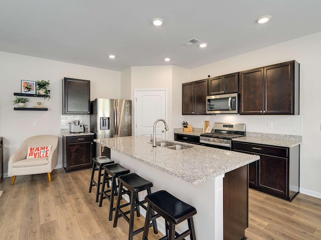 7231 Carrie Ct, Antioch, TN 37013 - kitchen with stainless steel appliances, a sink, a breakfast bar area, dark brown cabinetry, and backsplash