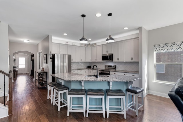 566 Oakvale Ln, Mount Juliet, TN 37122 - kitchen featuring appliances with stainless steel finishes, arched walkways, baseboards, a sink, and light stone counters