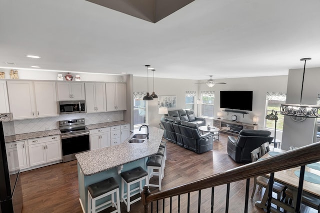 566 Oakvale Ln, Mount Juliet, TN 37122 - kitchen featuring appliances with stainless steel finishes, a sink, backsplash, light stone counters, and dark wood-type flooring