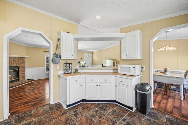 125 Fitzgerald Ave, Celina, TN 38551 - kitchen with white microwave, a textured ceiling, ornamental molding, arched walkways, and light countertops