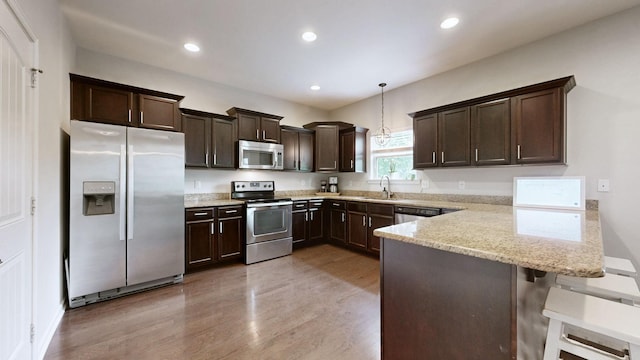 5127 Heroes Ln, Murfreesboro, TN 37129 - kitchen featuring appliances with stainless steel finishes, a sink, dark brown cabinets, a peninsula, and light wood-type flooring