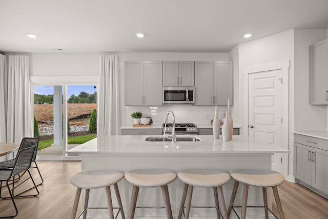 7214 Hanworth St, Fairview, TN 37062 - kitchen featuring stainless steel microwave, gray cabinetry, light wood-style flooring, a kitchen breakfast bar, and recessed lighting
