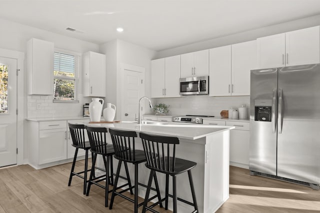 7218 Hanworth St, Fairview, TN 37062 - kitchen featuring appliances with stainless steel finishes, backsplash, light wood-style flooring, an island with sink, and recessed lighting